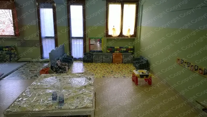 Sala giochi del Centro Prima Infanzia con materassini sul pavimento e scaffali lungo le pareti