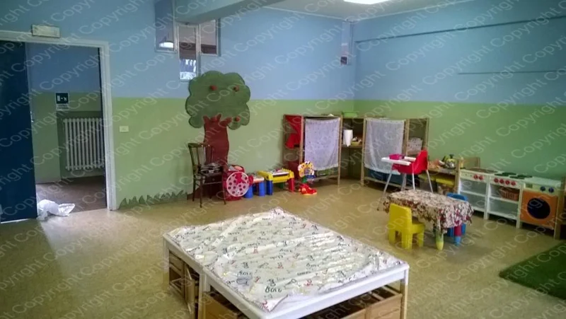 Sala del Centro Prima Infanzia con albero dipinto sulla parete e giochi colorati