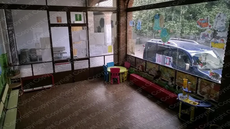 Ingresso vetrato del Centro Prima Infanzia con sedie e vista sul giardino esterno