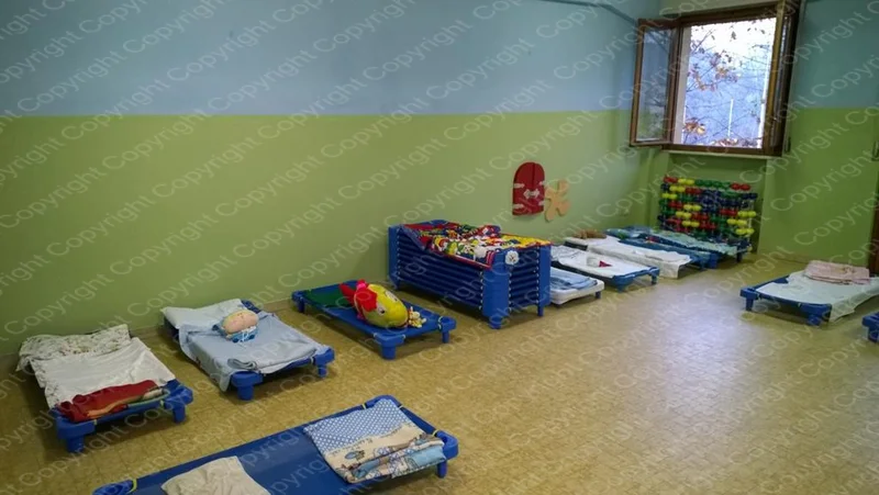 Sala nanna del Centro Prima Infanzia con brandine allineate sul pavimento e luce naturale dalla finestra