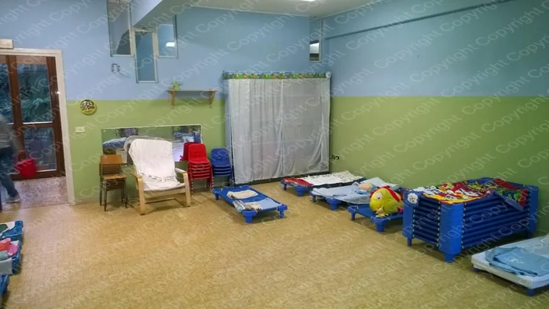 Sala del Centro Prima Infanzia con brandine, sedie e armadio per il riposo pomeridiano